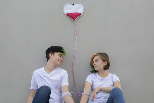 Teenager-Paar vor grauer Wand mit Infusionstropfen verbunden - PSTF01088