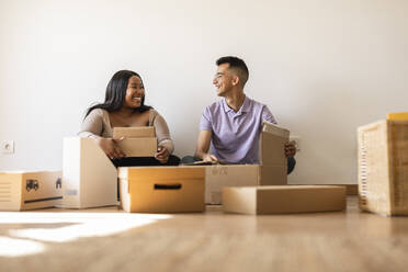 Happy couple unpacking cardboard boxes in new home - JCCMF10323