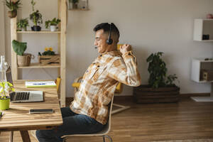 Freelancer stretching sitting on chair at home office - JCCMF10347