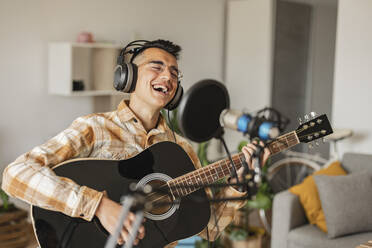 Glücklicher Mann singt und spielt Gitarre zu Hause - JCCMF10354