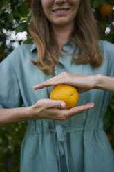 Woman holding ripe orange in hand - ANNF00166