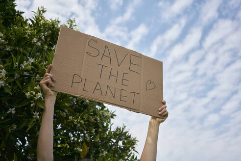 Hands of woman holding cardboard cut out with Save The Planet text under sky - ANNF00202