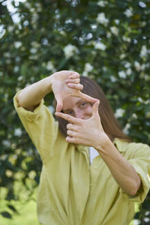 Woman making finger frame in garden - ANNF00215