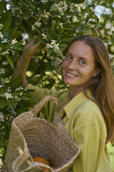 Happy woman near orange tree in orchard - ANNF00223