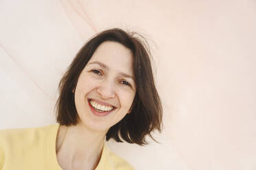 Smiling woman with short brown hair on pink background - EYAF02661