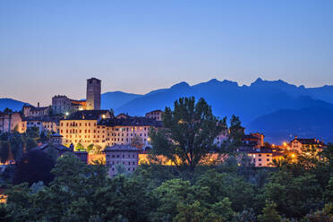 Italien, Venetien, Feltre, Beleuchtete Stadt in den Dolomiten in der Abenddämmerung - ANSF00383