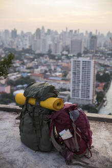 Trekking backpacks on rooftop with city in background - IKF00625