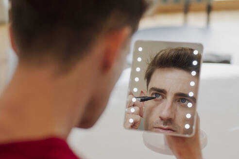 Man applying make-up looking in mirror - EGCF00098