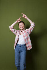 Happy woman dancing in front of green wall - MIKF00333