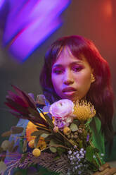 Young woman with colorful flowers and neon lights - YTF00824