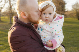 Vater küsst Tochter im Park auf die Wange - VIVF00920
