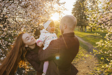 Family playing with daughter in park at sunny day - VIVF00925