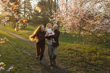 Glückliche Familie beim Laufen mit Tochter im Park - VIVF00929