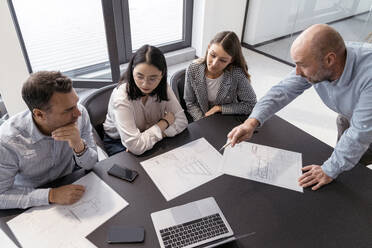 Business people working together on an architectural project in office - KMKF01955