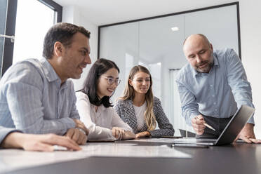 Business people working together on laptop in office - KMKF01957