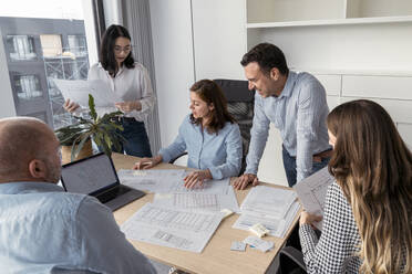 Business people working together on an architectural project in office - KMKF01966