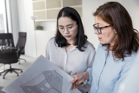 Zwei Geschäftsfrauen arbeiten gemeinsam an einem Architekturprojekt im Büro - KMKF01971