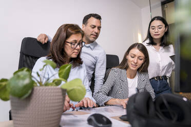 Business people working together on an architectural project in office - KMKF01993