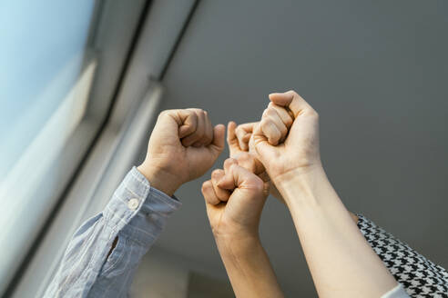 Raised fists of business people at the window - KMKF02007