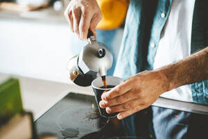 Hände eines Mannes, der Kaffee aus einer Kaffeemaschine in eine Tasse gießt - JOSEF19032