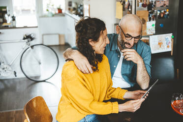 Mann und Frau teilen sich einen Tablet-PC und sitzen zu Hause - JOSEF19064