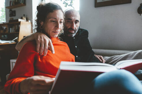 Mann und Frau lesen gemeinsam zu Hause ein Buch - JOSEF19143