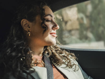 Woman enjoying sunlight sitting in car - MFF09309