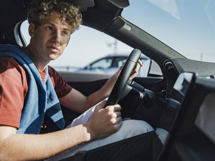 Junger Mann fährt Auto an einem sonnigen Tag - MFF09315