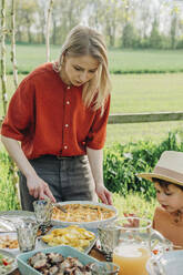 Mother cutting pie at dining table in back yard - VSNF00811