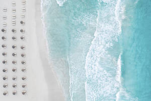 Spain, Balearic Islands, Formentera, Drone view of rows of umbrellas on empty beach - MMAF01460