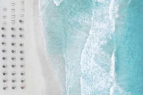 Spain, Balearic Islands, Formentera, Drone view of rows of umbrellas on empty beach - MMAF01460