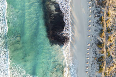 Spanien, Balearische Inseln, Formentera, Drohnenaufnahme von Reihen von Sonnenschirmen am leeren Strand - MMAF01465