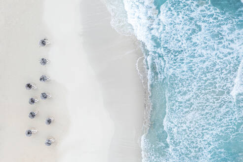 Spain, Balearic Islands, Formentera, Drone view of rows of umbrellas on empty beach - MMAF01471