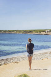 Spain, Balearic Islands, Formentera, Woman standing alone on Mediterranean beach - MMAF01472