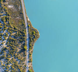 Spanien, Balearische Inseln, Formentera, Drohnenansicht einer leeren Straße entlang der türkisfarbenen Küste - MMAF01476
