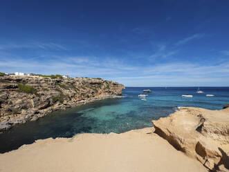 Spanien, Balearische Inseln, Formentera, Strand mit Klippen und Booten im Hintergrund - MMAF01487