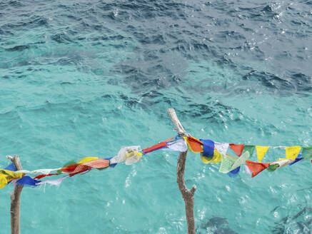 Spain, Balearic Islands, Formentera, Colorful fabrics hanging against coastal water - MMAF01488