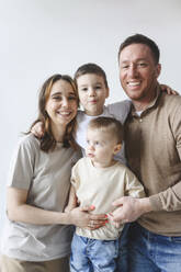 Glücklicher Vater und Mutter mit Söhnen vor weißem Hintergrund - EYAF02675