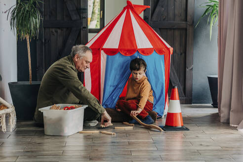 Großvater und Enkel spielen zu Hause mit Spielzeugeisenbahnen - VSNF00830
