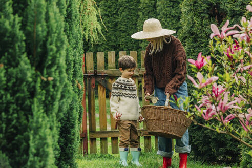 Mutter mit Sohn hält Weidenkorb im Garten - VSNF00863