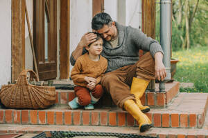Vater umarmt Sohn auf den Stufen eines Hauses sitzend - VSNF00875