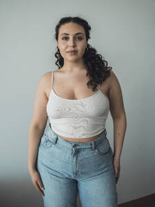 Confident curvy woman standing in front of wall - MFF09376