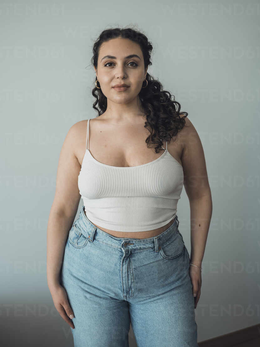 Confident curvy woman standing in front of wall stock photo
