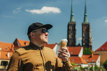 Mann mit Sonnenbrille hält Eis an einem sonnigen Tag - VSNF00876