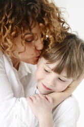 Mother with curly hair kissing son - EYAF02687