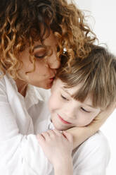 Mutter mit lockigem Haar küsst Sohn - EYAF02687