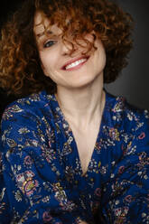 Happy woman with curly hair wearing floral dress - EYAF02693