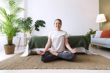 Woman with diabetes practicing lotus position at home - AAZF00520