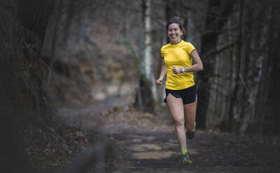 Happy woman running on footpath in forest - SNF01648