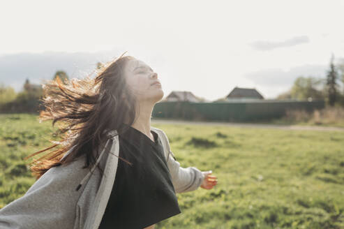 Carefree girl with arms outstretched in field - ANAF01419